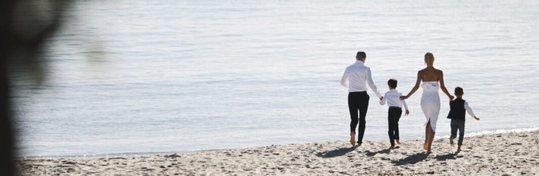 Back view of running family on the beach on the sunny day near t